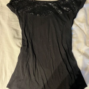 Svart topp med paljettdetalj från Anna Field - Säljer en svart topp från Anna Field med snygg paljettdetalj över axlar och bröst. Toppens material känns mjukt och stretchigt, perfekt för att lyfta en outfit med lite extra glans.