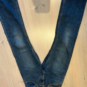 Levis 503 mörkblå jeans - Mörkblå Levis 503 jeans med klassisk femficksdesign och raka ben. Jeansen har en tydlig Levis-lapp bak i midjan. Litet hål i byxbenet