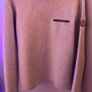 Ljusgrå sweatshirt från Sail Racing - Säljer en stilren ljusgrå sweatshirt från Sail Racing. Tröjan har rund hals, lång ärm och en diskret svart detalj på bröstet samt logotyp på ärmen. Perfekt för en avslappnad och sportig look.