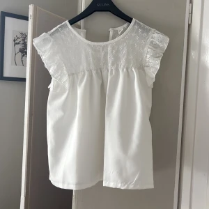 Vit blus med spets och volang - Supersöt vit blus med broderad spets upptill och volangdetaljer på axlarna. 💕