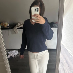 Mörkblå stickad tröja Bá Thiên - Mörkblå stickad tröja från Bá Thiên med v-ringning och diskreta lodräta ränder upptill. Tröjan har lång ärm och ribbade muddar vid ärmslut och nederkant. Perfekt för dig som gillar en enkel men snygg look.