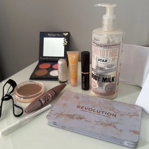 Stort sminkpaket med paletter & mascara - Allt för 50kr!! Säljer ett sminkpaket med Revolution ögonskuggspalett i varma toner, ansiktspalett med rouge, contour och setting powder, Maybelline Lash Sensational mascara, Essence vit kajal, W7 läppglans, Essence highlighter, Bobbi Brown stick, bronzer och ögonfransböjare.