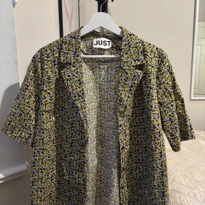 Blommig skjorta från JUST Female - Kortärmad skjorta från JUST Female med blommigt mönster. Knappt använd. Nypris: 1000kr