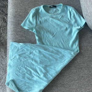 Ljusblå ribbad klänning från FB Sister - Supersöt ljusblå ribbad klänning från FB Sister i storlek S. Klänningen har korta ärmar, rund halsringning och är i ett mjukt, stretchigt material. Perfekt för dig som gillar en enkel och fräsch look!