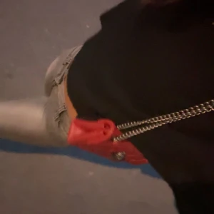 Röd Kurt geiger väska  - Snygg röd axelväska i quiltat skinn med cool silverfärgad kedja och unik dekoration på locket. Perfekt storlek för det viktigaste och ger en edgy vibe till din outfit. Väskan har ett stilrent och trendigt utseende som sticker ut.