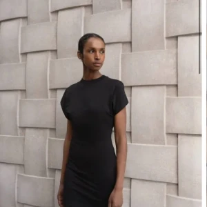 Svart t-shirtklänning från Avora - Svart t-shirtklänning från Avora med rund halsringning och korta ärmar. Klänningen har en rak, slim passform och är tillverkad i mjuk bomull. Minimalistisk design med diskret Avora-logga framtill. Perfekt för en clean och stilren look. Storlek m