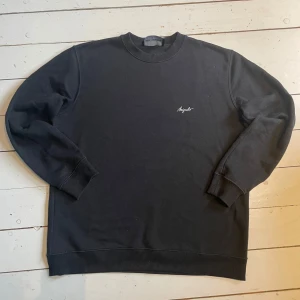 Svart sweatshirt från Axel Arigato - En stilren svart sweatshirt från Axel Arigato med diskret logga broderad på bröstet. Tröjan har rund hals, ribbade muddar och är tillverkad i mjuk bomull. Perfekt för en clean och avslappnad look. Pris kan diskuteras vid snabbt köp. 