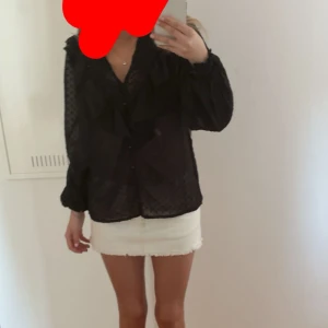 Svart prickig blus med volang  - Supersöt svart blus från Boohoo med prickigt mönster, volangdetaljer och v-ringning. Blusen är transparent och har långa ärmar med lätt puff och knappar framtill. 🌸