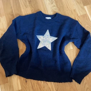Mörkgrå stickad tröja med stjärna från gina - Mysig mörkblå stickad tröja med en stor silverfärgad stjärna framtill. Tröjan har rund halsringning och långa ärmar, perfekt för dig som gillar en enkel men ändå cool look. Kan skicka fler bilder om någon vill💕