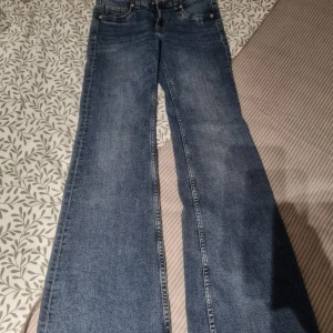 Blå bootcut jeans från Divided, strl 32 - Snygga blå jeans från Divided i klassisk bootcut-modell. Jeansen har normal passform, fem fickor och är tillverkade i ett mjukt bomullstyg med lite stretch. Perfekta för dig som gillar retrovibbar och breda ben.