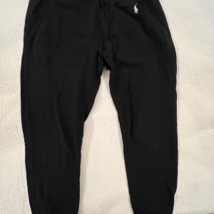 Svarta mjukisbyxor Polo Ralph Lauren - Svarta mjukisbyxor från Polo Ralph Lauren med klassisk broderad logga på höften. Byxorna har resår i midjan och vid bensluten, samt sidofickor. Perfekta för chill dagar eller när du vill vara bekväm men ändå se snygg ut. Lite dammiga på bilden så tvättas innan jag skickar dom!😊