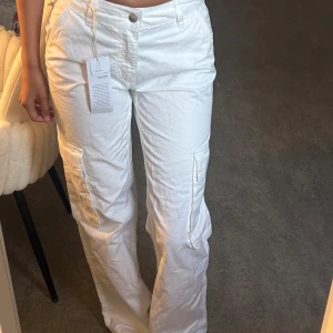 Vita cargopants - Säljer ett par vita cargopants,  stora fickor på sidorna och därbak. Aldrig användts, helt nya! 32 men passar 34