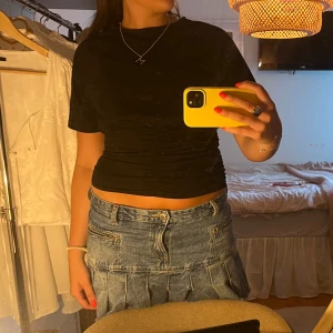 Svart topp med rynk framtill - Säljer en svart topp med korta ärmar och snygg rynkdetalj framtill. Toppen har en tight passform runt magen och lösare passform runt armarna och bysten🙌🏼🙌🏼🙌🏼