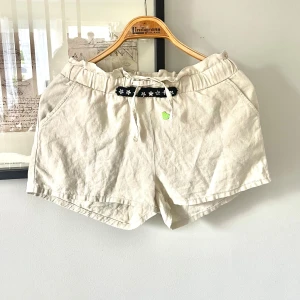 Linneshorts från Lindex - Säljer ett par linneshorts från Lindex som dottern ”pimpat” genom att sätta på en söt blommig rand på linningen. Det finns även ett grönt hjärta strax under bården som hon också satt dit. Byxorna är i strl 152 men dottern har strl 36 och har använt dem så de passar den storleken. De är i mycket gott skick men sätter lågt pris pga dotterns ”statement” att inte hennes kläder ska se ut som någon annans ;P De textilmärjen hon satt på är lite ”hårda” men inget som känns när man har dem på sig.De har 