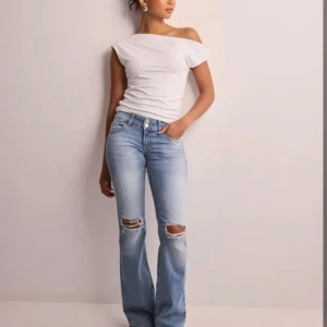 Ljusblå bootcut jeans med slitningar - Snygga ljusblå jeans med bootcut passform och slitna detaljer vid knäna. Medelhög midja och bakfickor med lock och knapp. 🌸