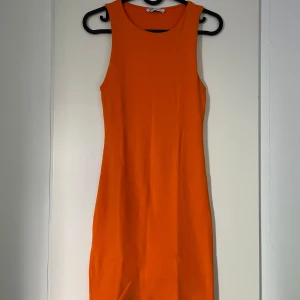 Orange ärmlös kortklänning - En snygg figursydd orange klänning från Zara. Den är endast använd fåtal gånger.