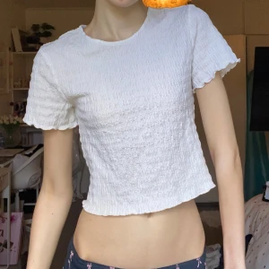 Vit topp - Superfin vit topp från Vero Moda med korta ärmar och smockad struktur. T-shirten har vågiga kanter vid ärmslut och nederkant, vilket ger en söt och trendig look😍Perfekt till jeans eller kjol för en chill vibe💕Storlek S, men passar XS också men då blir den lite lösare vid midjan! Använd några gånger, inga fel💋