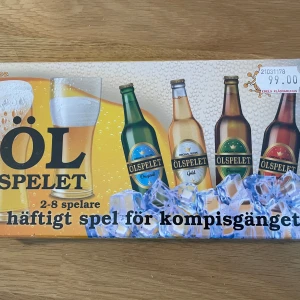 Ölspelet sällskapsspel - Roligt sällskapsspel för 2-8 spelare med ölfokus, perfekt för kompisgänget. Spelet har en färgglad framsida med illustrationer av olika ölflaskor och isbitar. Lådan är rektangulär och har en gul och blå design.