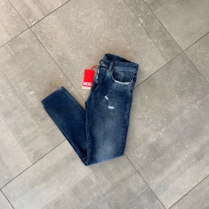 Mörkblå jeans från Diesel - Snygga blå jeans från Diesel med en klassisk femficksdesign. De har en lätt slitning på framsidan för en trendig look. Nyskick på jeansen och alla tags kvar. Stolek: W29 Nypris:1999kr