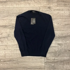 Mörkblå kashmirtröja från Lawrence Grey - Mörkblå rundhalsad tröja från Lawrence Grey i 100% kashmir. Klassisk modell med långa ärmar och ribbade muddar vid ärmslut och nederkant. Perfekt för dig som gillar stilrena och mjuka plagg. | Skick: 9/10 endast använd ett par gånger | Mitt pris: 649kr | Material: 100% Kashmir | Hör gärna av dig vid fler frågor!