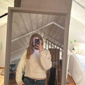 Vit stickad tröja från Monki - Säljer en krämvit stickad tröja från Monki i storlek S. Tröjan har ett diskret hjärtmönster, ribbade muddar och är croppad i modellen. Perfekt för kyligare dagar och enkel att matcha med jeans eller kjol.