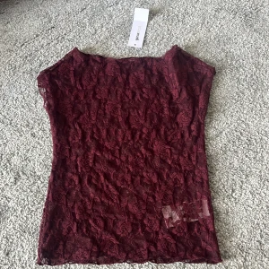 Vinröd spetsblus från Gina Tricot - Vinröd, ärmlös blus i spets från Gina Tricot. Storlek XS. Jag har aldrig använt den och prislappen sitter kvar. Nypris 299,95
