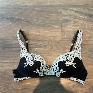 Intimissimi Bh - Snygg svart bh med vit spets och broderade detaljer. Justerbara axelband med spets och hakknäppning bak. Säljer då den inte passar längre 