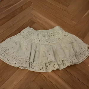 Grön broderad volangkjol från Zara - Supersöt grön kjol med broderade blommor och volangkant. Kjolen har elastisk midja och är i kort modell. Perfekt för en somrig look.