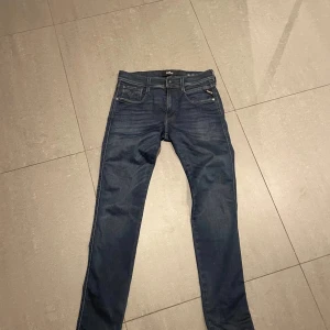 Mörkblå Replay jeans - Snygga mörkblå jeans från Replay i modellen Anbass. De har en klassisk femficksdesign med dragkedja och knapp framtill. Perfekta för en stilren look. Helt nyskick och aldrig burits. Snygg tvätt och flex