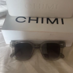  CHIMI 04 grey - Stilrena solglasögon från CHIMI i transparent grå plast med fyrkantig form. Snygg och modern design som passar till många olika looks. Kommer med originalfodral.