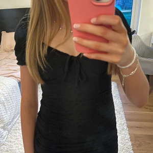 Svart kortklänning från H&M - Supersöt svart klänning från H&M med puffärmar och broderade detaljer. Klänningen har en söt knytning vid bysten och är figurnära med kort längd. Perfekt för dig som gillar romantisk och trendig stil. Den har superskönt material som är jättebra för varma dagar, hör av er om frågor❤️