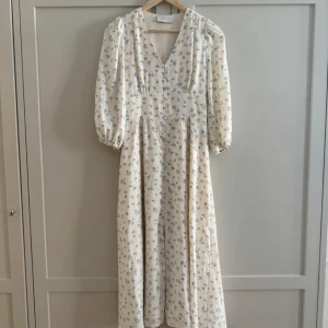 Vit blommig långklänning med v-ringning - Klänning från neo noir. Storlek xs nyskick. Nypris 1299, slutsåld från förra året