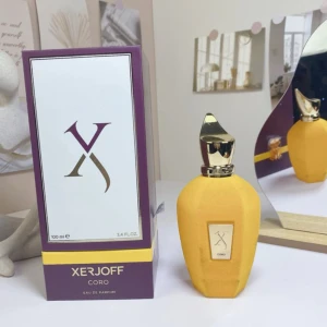 Xerjoff Coro Eau de Parfum 100ml - Lyxig parfym från Xerjoff i modellen Coro. Flaskan är matt gul med en unik, guldig metallkork och geometrisk form. Kommer i en elegant lila och vit box med guldiga detaljer. Perfekt för dig som gillar exklusiva dofter och snygg design.