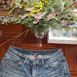 Blå jeansshorts Love Me Love You - Snygga blå jeansshorts från Love Me Love You i klassisk femficksmodell med slitna detaljer och uppvikta ben. De har normal passform och midwaist, perfekt för dig som gillar en chill och avslappnad stil. Materialet är slitstarkt denim och färgen är tvättad blå.passsar inte mej så säljer de.