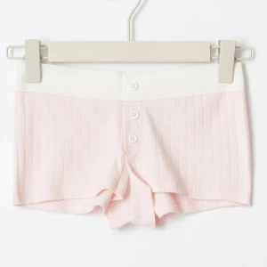 Gina Young pyjamas shorts - Supermjuka ljusrosa shorts med ribbad struktur och diskreta små hålmönster. Bred, elastisk midja i vitt och tre vita knappar framtill ger en chill och söt look. Perfekta för varma dagar eller som mysplagg hemma.