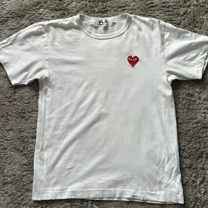 Vit Cdg t-shirt - Vit t-shirt från Comme des garcons, som jag har köpt i NK. Säljer för att den har blivit för liten. Den är i använt skick därav priset. Nypris ligger den på 1000kr. Står size M men sitter som S