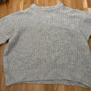 Grå stickad tröja  - Säljer en ljusgrå stickad tröja från 157 i storlek M. Tröjan har en ribbad hög hals och grovstickad struktur som ger en chill och mysig vibe. Långa ärmar med breda muddar och relaxed passform. Perfekt för kalla dagar när du vill vara både bekväm och snygg.