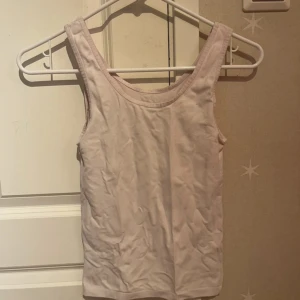 Ljusrosa linnetopp från Benetton - Enkel och stilren ljusrosa linnetopp från United Colors of Benetton. Toppen är ärmlös med klassisk rund halsringning och tillverkad i mjuk bomull. Perfekt att matcha med jeans eller kjol för en clean look.