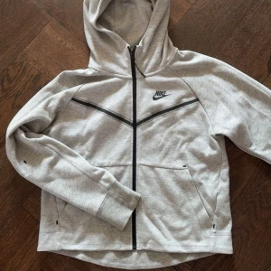 Grå nike tech kofta XS - Säljer en grå Nike tech tröja i size XS. Koftan är knappt använd eftersom den är för liten. Pris kan diskuteras och om mer bilder behövs så är det bara och skriva!
