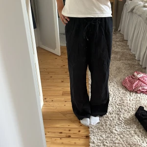 Svarta vida linnebyxor med snörning - Säljer ett par svarta linnebyxor med avslappnad passform och snörning i midjan. Byxorna är vida i modellen och perfekta för en chill och stilren look. Sköna att bära och lätta att matcha med olika toppar.