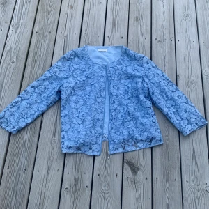 Blommig blå cardigan jacka från Gerry Weber - Supersöt ljusblå cardigan jacka från Gerry Weber med blommigt spetsmönster över hela jackan. 