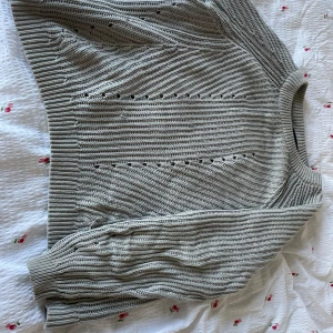 Beige stickad tröja med hålmönster - Säljer en beige stickad tröja med snygga håldetaljer och ribbad struktur. Tröjan har rund hals och långa ärmar, perfekt för dig som gillar en chill och stilren look. Passar dig som vill ha något mjukt och bekvämt till hösten eller vintern.