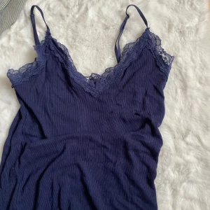 Mörkblå ribbad linnetopp från Amisu - Supersöt mörkblå linnetopp från Amisu med tunna axelband och v-ringning. Toppen har ribbad struktur och spetsdetaljer längs urringningen som ger en extra touch. Perfekt att styla med jeans eller kjol för en chill look.