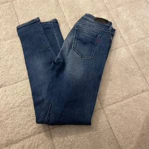 Replay blå skinny jeans - Storlek: W27, L30. Snygga blå Replay jeans med klassisk femficksdesign och skinny passform. Jeansen har en mörk tvätt med lätt slitning på låren och smalare ben. Perfekta för dig som gillar en modern och stilren look.