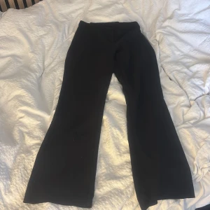 Svarta bootcut/raka kostymbyxor från Kappahl  - Svarta bootcut byxor från Kappahl i storlek 36. Tillverkade i en mjuk blandning av viskos och polyester som ger en skön känsla och snyggt fall. Klassisk look med utsvängda ben, perfekta till sneakers eller boots. Dom har varit in sydda men är nu uppspröttade