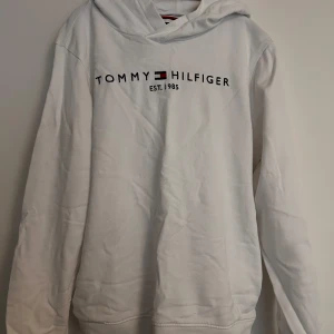 Vit hoodie från Tommy Hilfiger - Vit hoodie från Tommy Hilfiger med broderad logga och text på bröstet. Köpt på kids brandstore i unisex modell.