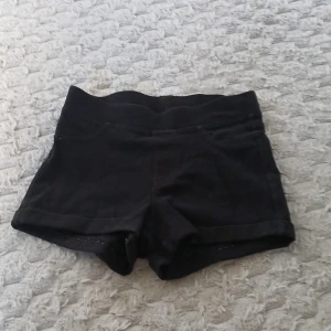 Svarta shorts från H&M - Svarta shorts från H&M. De har uppvikta benslut och är gjorda i mjukt bomullstyg som känns skönt mot huden. Perfekta för varma dagar och enkla att matcha med din favorit-topp. Dom är inte hög midjade men inte lågmidjade 