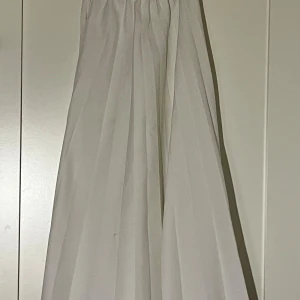 Vit långkjol - Säljer en vit långkjol i storlek 36. Kjolen har bred resår i midjan och ett snyggt fall med tydliga veck. Vet inte märke