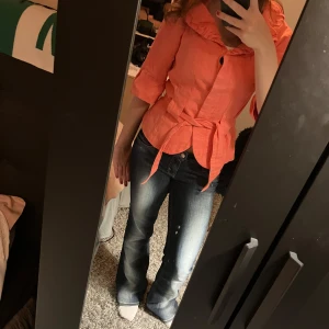 Corall färgad blus med volang och knyt - Säljer en snygg corall blus med volangkrage och knytband i midjan. Blusen har trekvartsärm  och är väldigt cool men något som tyvärr inte kommer till användning 💗