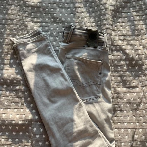 Replay Anbass ljusgrå jeans, stl 28/32 - Säljer ett par snygga Replay Anbass jeans i ljusgrå färg. Modellen har smal passform med klassiska fem fickor och detaljerade sömmar på bakfickorna. Jeansen är tillverkade i mjukt bomullsmaterial med lite stretch för extra komfort. Jeansen är i mycket bra skick och har inga defekter, nypris ca 1500. Storlek 28/32!